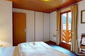A bedroom with a bed and a window with the word alpine on it