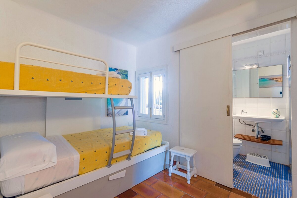A bunk bed with yellow sheets is next to a bathroom