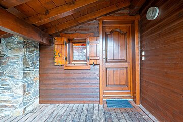 A wooden door with a window with shutters on it