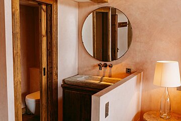 A bathroom with a sink and a round mirror
