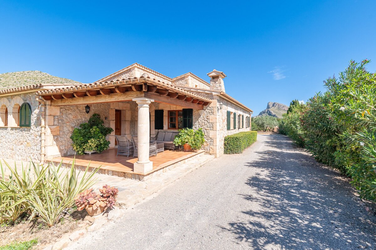 A stone house with a porch and a mountain in the background