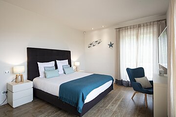 A bedroom with a large bed and a blue chair