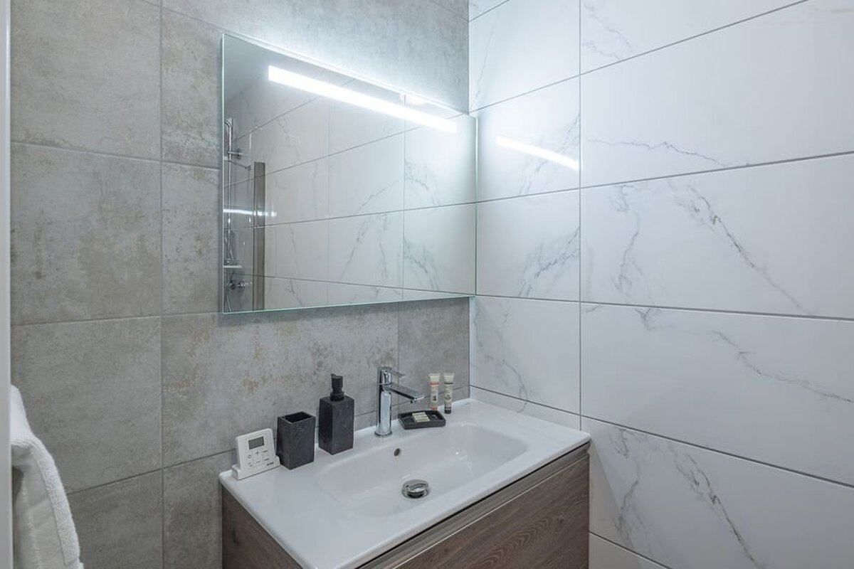 A bathroom with marble tiles and a sink and mirror
