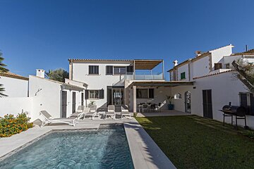 A white house with a swimming pool in front of it