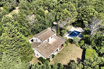 An aerial view of a house surrounded by trees and a pool