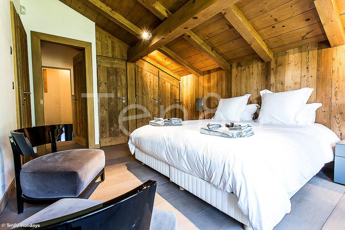 A bed with white sheets and pillows in a room with wooden walls