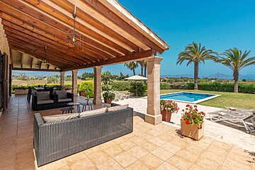 A patio with a couch and chairs and a pool in the background