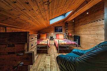 A bedroom with two beds and a blue chair