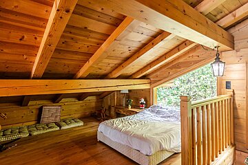 A bedroom with a wooden ceiling and a bed