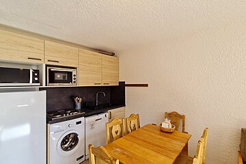 A kitchen with a washing machine and a microwave