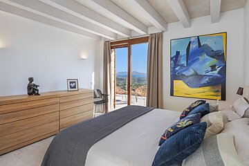 A bedroom with a large bed and a painting on the wall