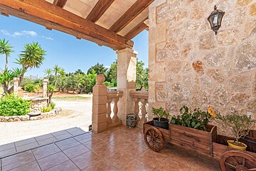 A porch with a wooden cart filled with potted plants