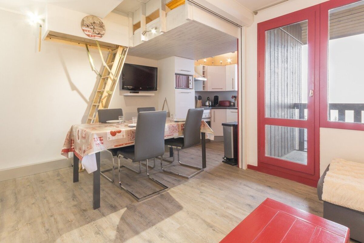 A dining room with a table and chairs and a red door