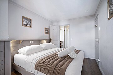 A bedroom with a bed and two pictures on the wall