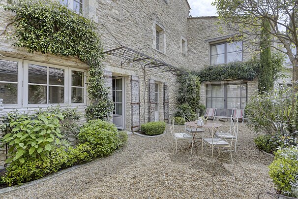 A patio with a table and chairs in front of a stone building