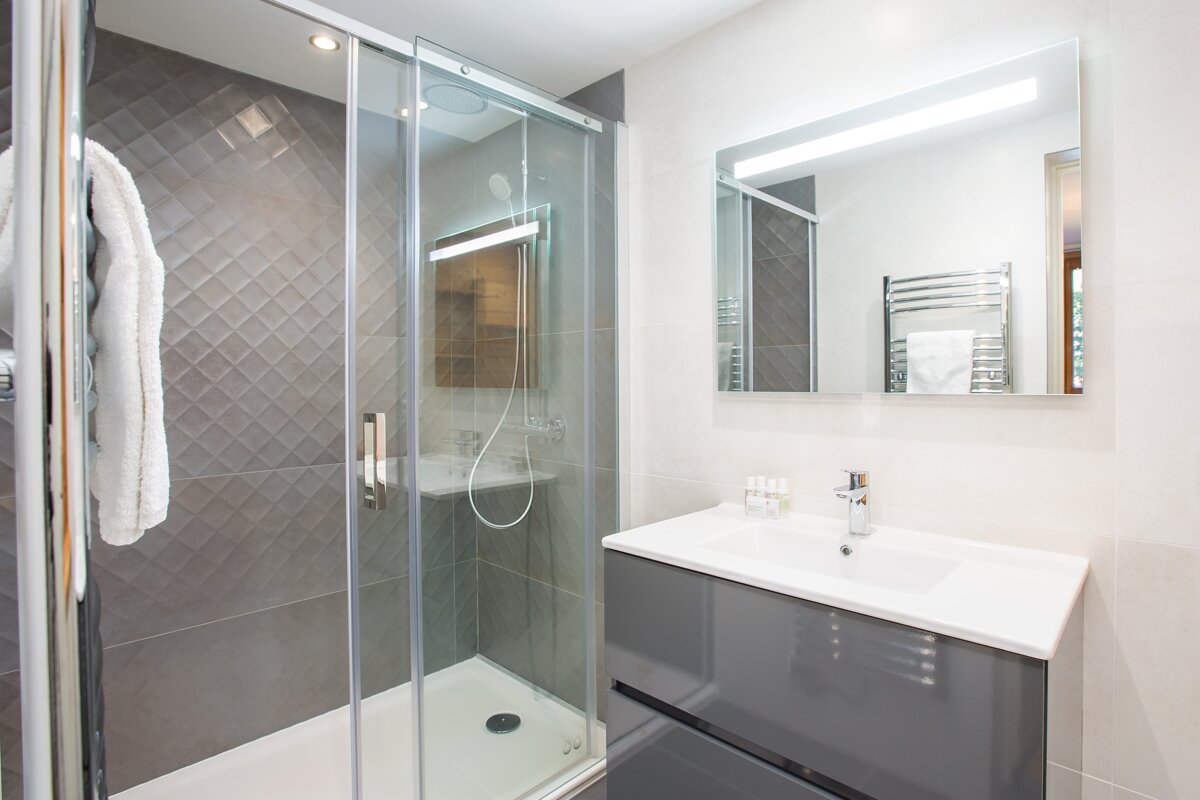A bathroom with a walk in shower and a sink