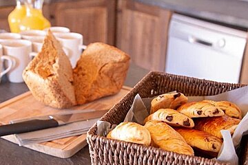 A basket of pastries sits on a counter next to a loaf of bread
