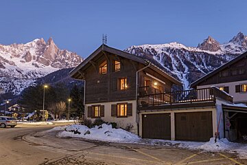 A house with a balcony and mountains in the background