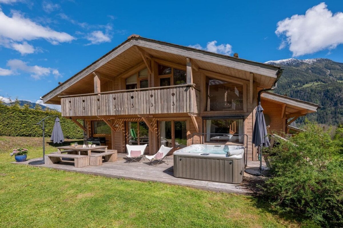A large wooden house with a hot tub in front of it