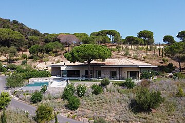 A house with a swimming pool is surrounded by trees