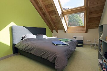 A bedroom with a large bed and a skylight