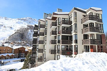 A building with a lot of balconies is covered in snow