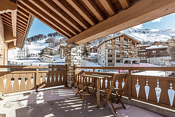 A balcony with a table and chairs in the snow