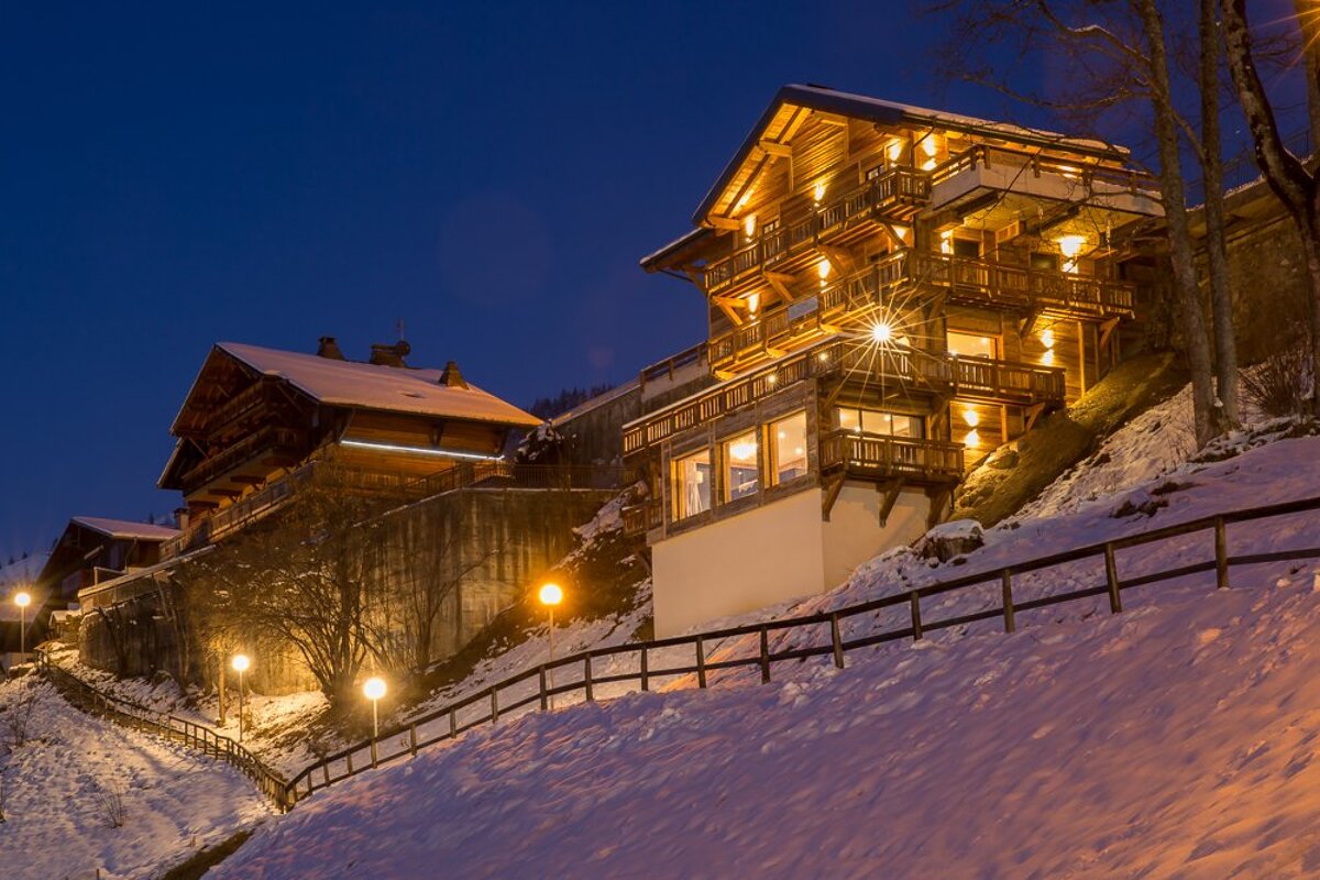 A large wooden house is lit up in the snow