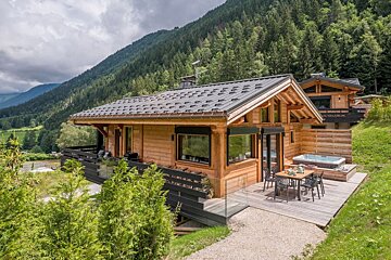 A small wooden house with a hot tub in front of it