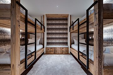 A room with four bunk beds and a bench