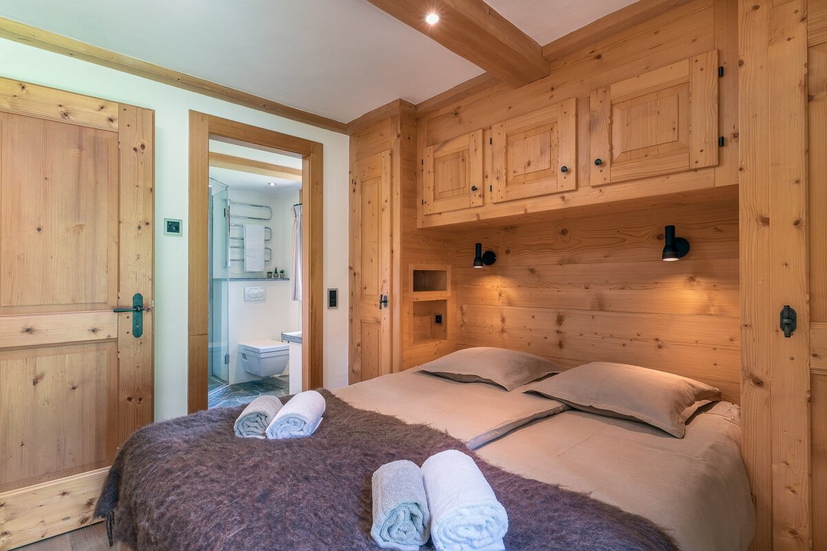 A bedroom with wooden walls and a bed with towels on it