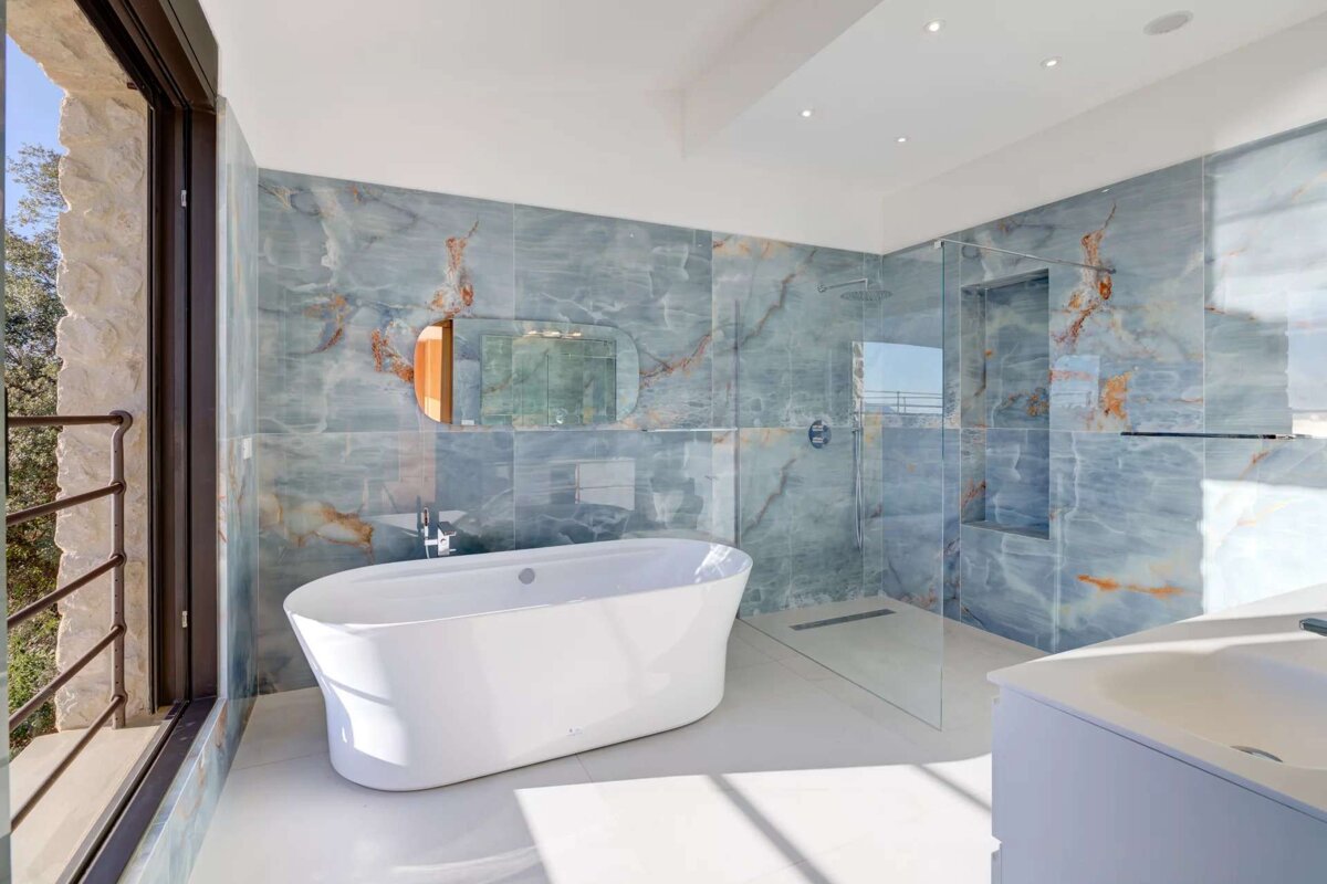 A bathroom with blue marble tiles and a bathtub
