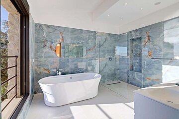 A bathroom with blue marble tiles and a bathtub