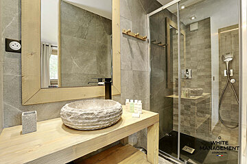 A bathroom with a stone sink and a glass shower