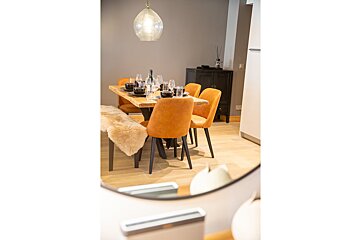 A dining room with a table and chairs and a mirror