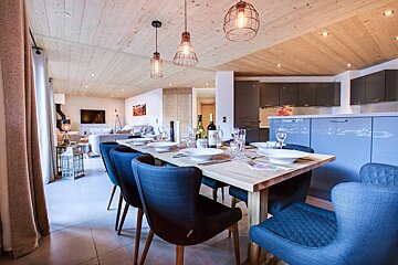 A dining room table with a bottle of wine on it
