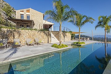 A large swimming pool in front of a stone house