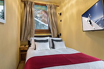 A bedroom with a bed and a television with a picture of a skier on it