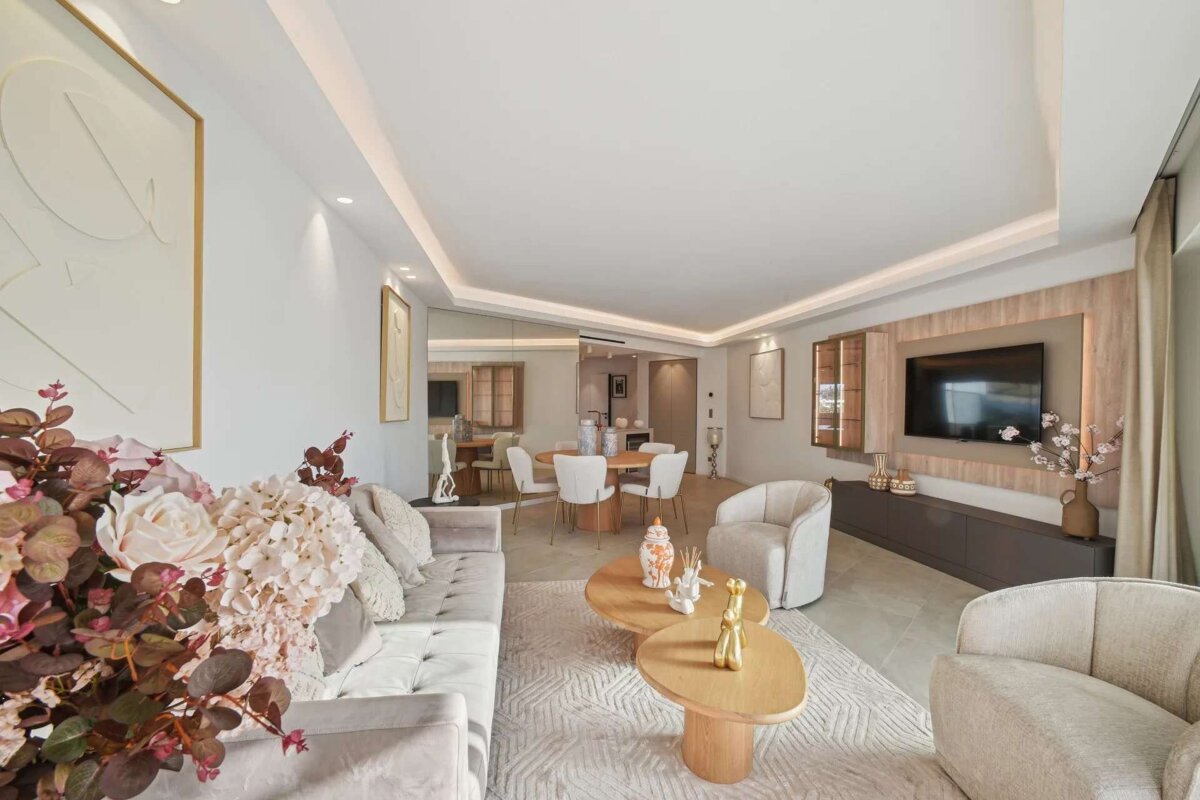 A chic, open-plan living and dining space with contemporary furniture, subtle lighting, warm neutral colors, and an elegant floral display.