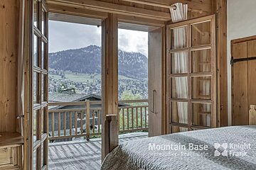 A bedroom with a mountain base real estate logo on the wall