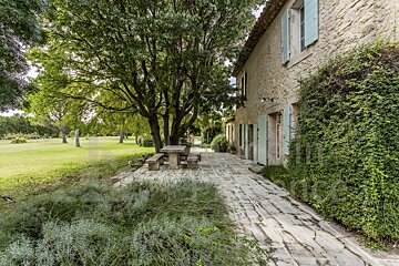 A stone walkway leads to a house with blue shutters