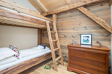A wooden bunk bed with a ladder and a dresser