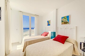 A bedroom with two beds and two paintings on the wall