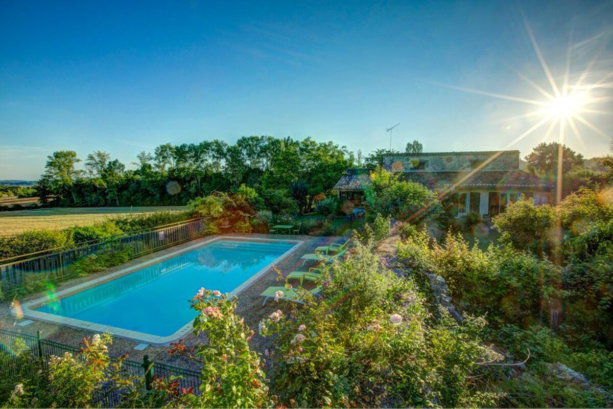 The sun shines brightly over a large swimming pool
