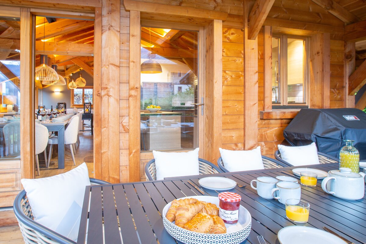 A bowl of croissants sits on a table next to a jar of jam