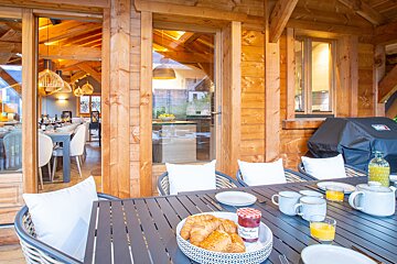 A bowl of croissants sits on a table next to a jar of jam