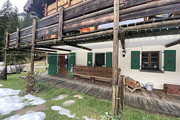 A wooden house with green shutters and a bench