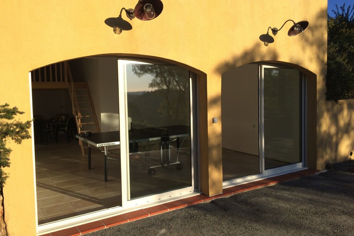 A ping pong table sits in front of a sliding glass door