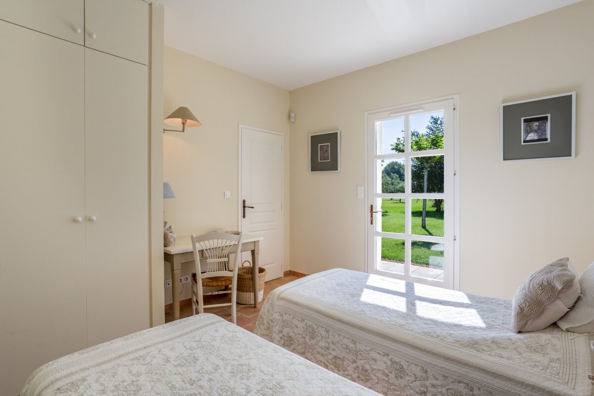 A bedroom with two beds a desk and a picture on the wall