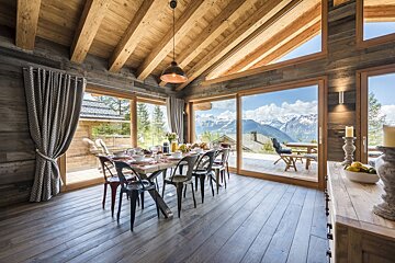 A dining room with a table and chairs and a view of the mountains